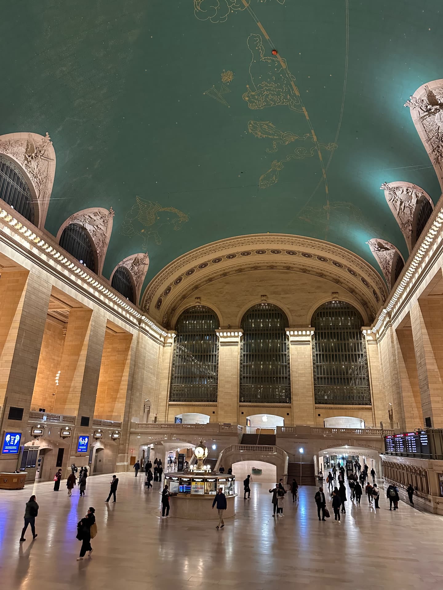 Grand Central Terminal's main concourse with its green constellation ceiling, arched windows and the information booth clock