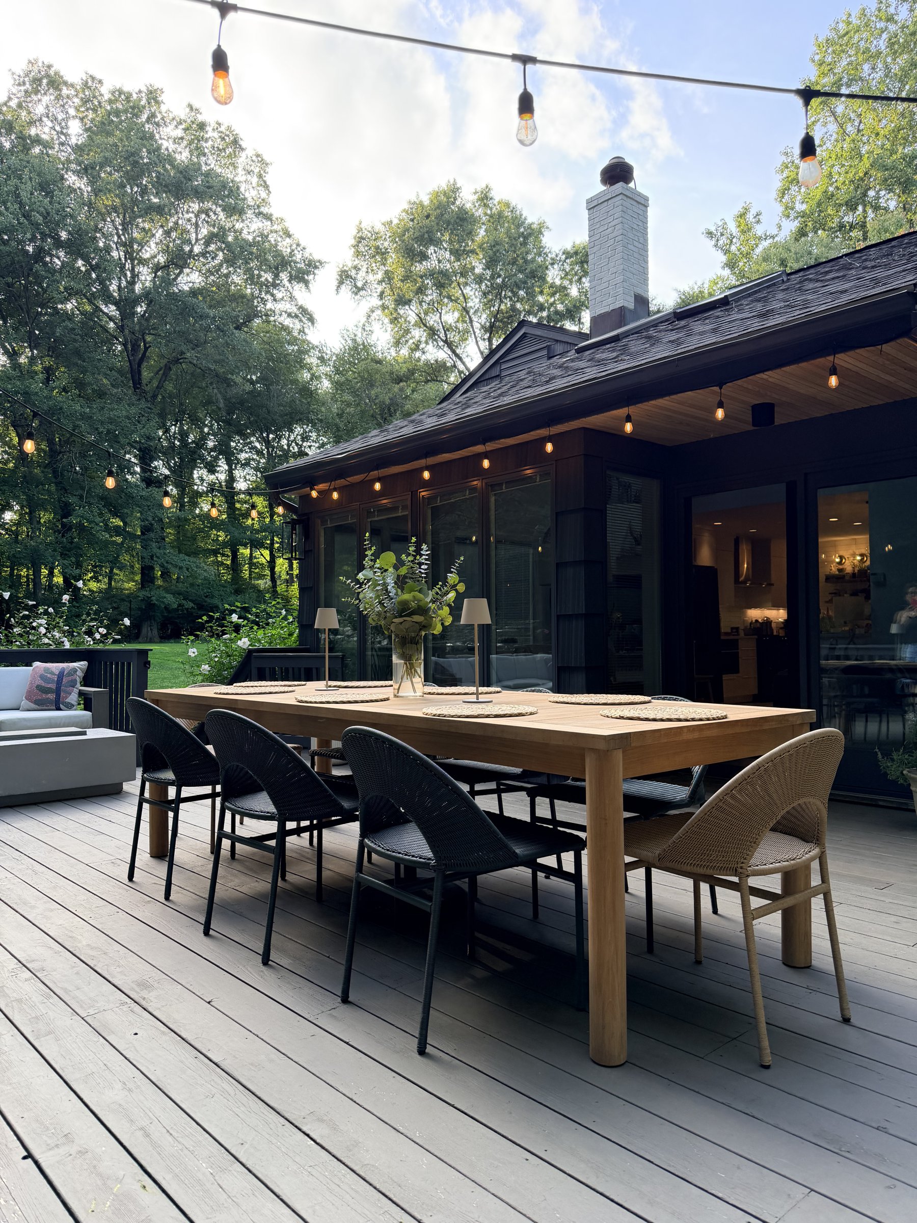 Long wooden table and chairs on a deck under string lights